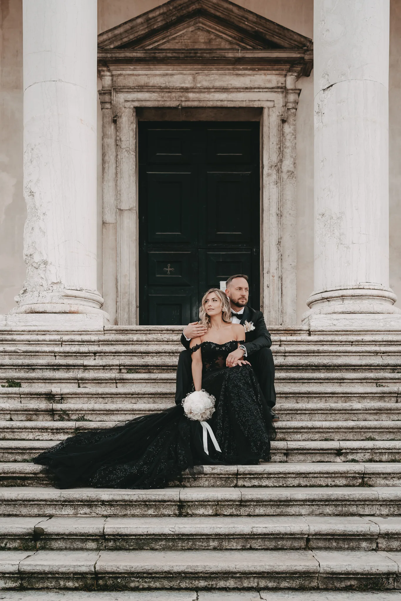 Brautpaar in Venedig auf historischen Marmortreppen, umgeben von majestätischen Säulen – ein eleganter Moment der Hochzeit in Venedig.