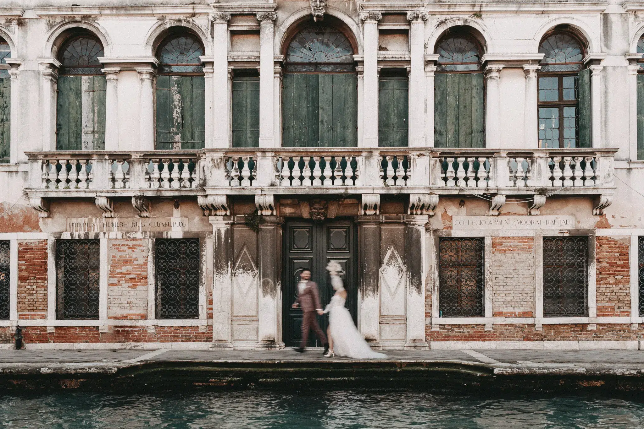 Bewegungsaufnahme eines Brautpaares vor einer prächtigen venezianischen Fassade am Kanal – einzigartig heiraten in Venedig.