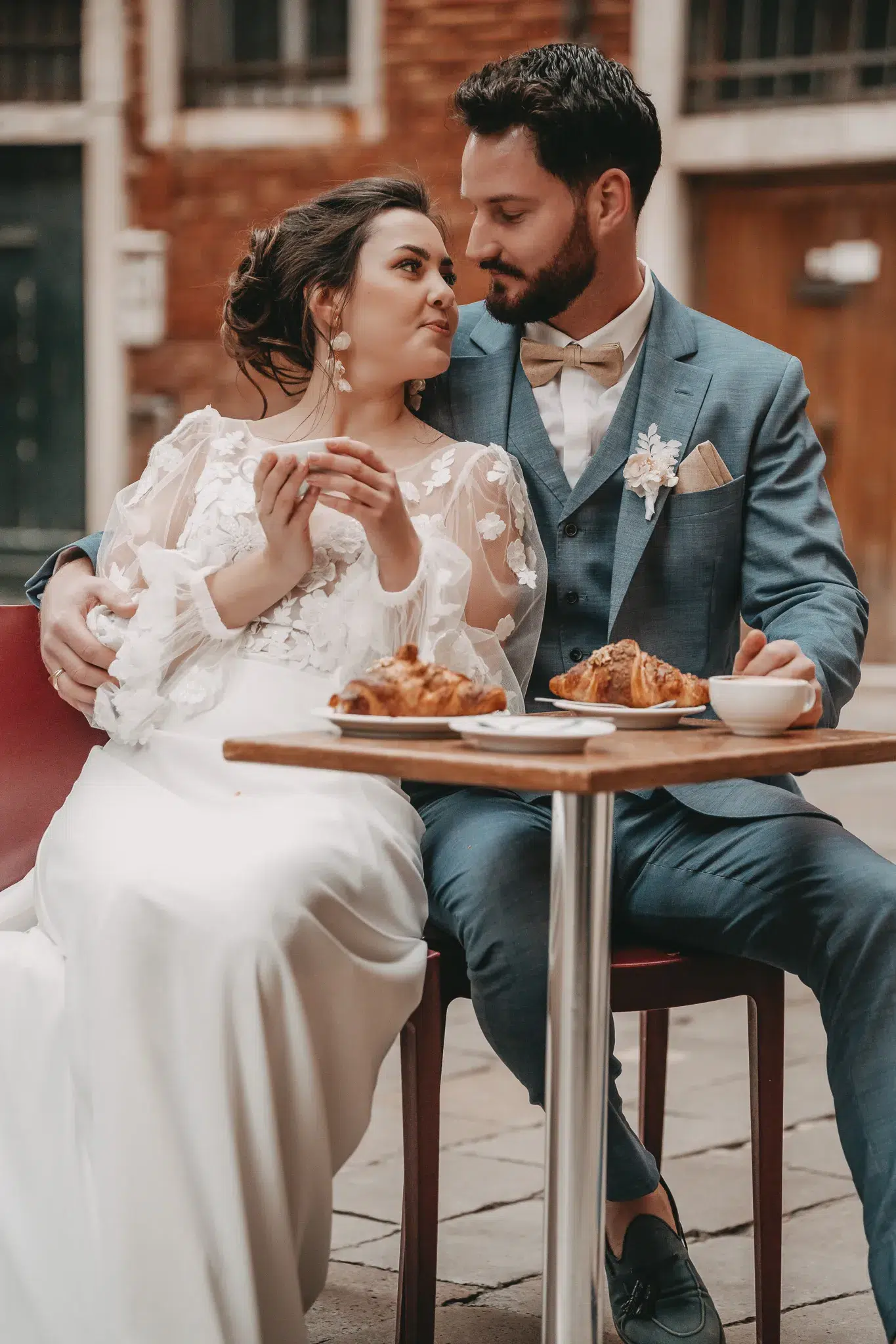 Brautpaar genießt Kaffee und Croissants in einem Café in Venedig – ein entspannter Hochzeitsmoment.