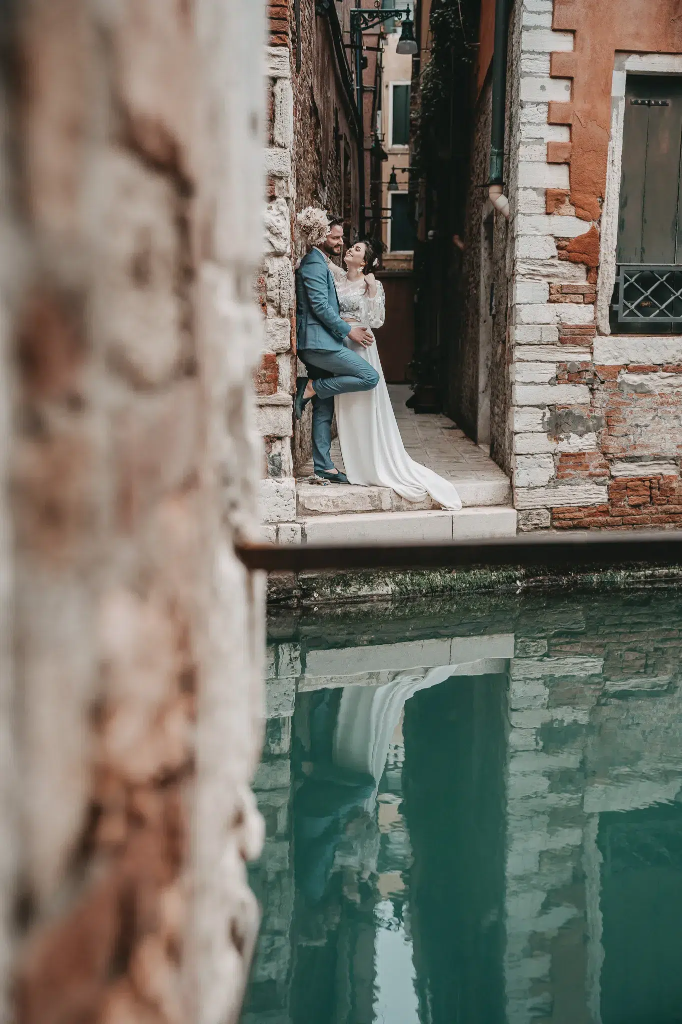 Brautpaar in einer romantischen Gasse in Venedig mit Spiegelung im Kanal – stilvoll heiraten in Venedig.