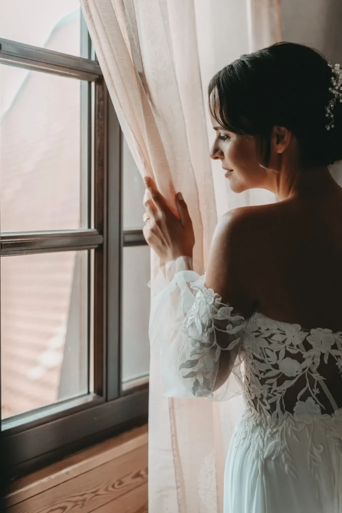 Hochzeitsfotograf Pfalz fotografiert Braut bei Blick aus dem Fenster