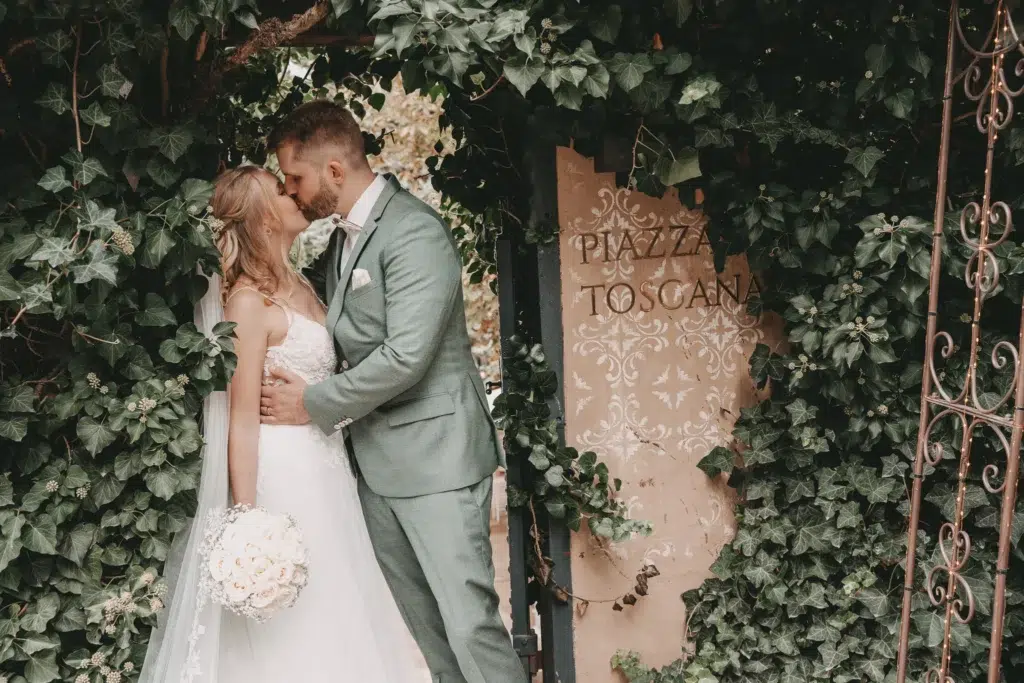 Hochzeitsfotograf Morrhof fotografiert küssendes Brautpaar am Eingang zur Piazza Toscana