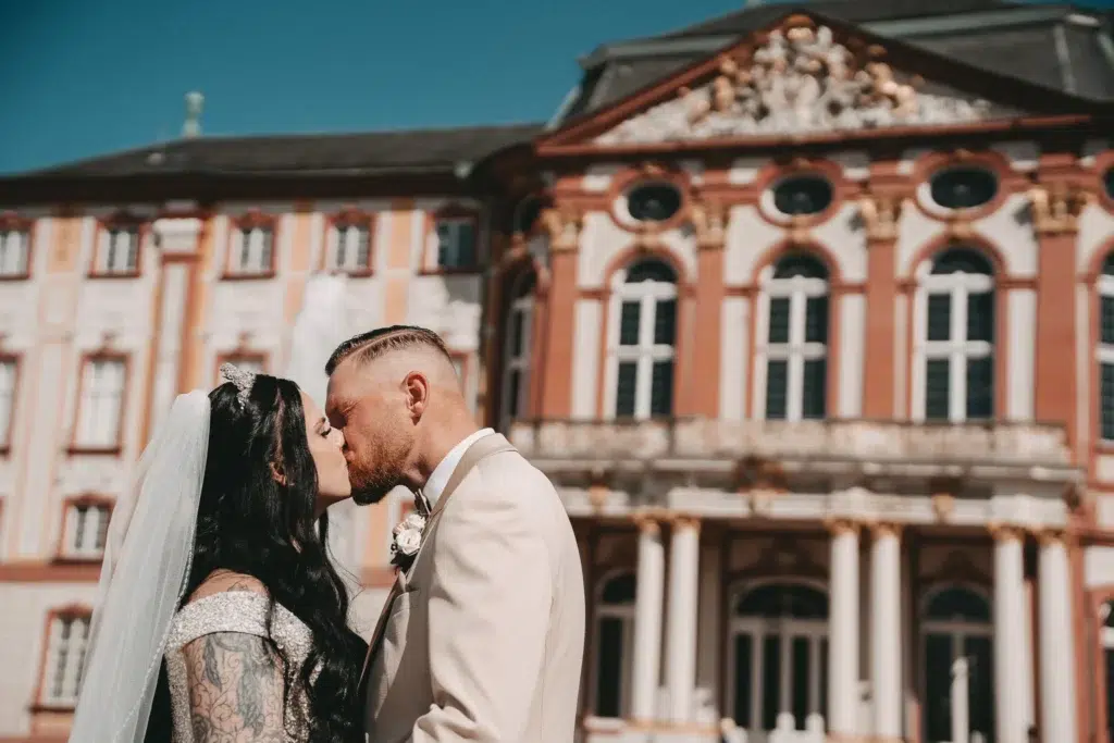 Brautpaar küsst sich vor historischem Barockschloss in der Karlsruher Region